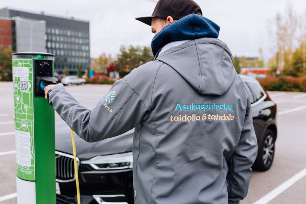 Sähköautot yleistyvät vaihdilla. Kuvituskuva henkilöstä, joka lataa sähköautoa. 